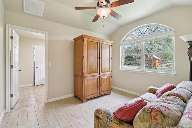 living area featuring lofted ceiling, baseboards, visible vents, and ceiling fan