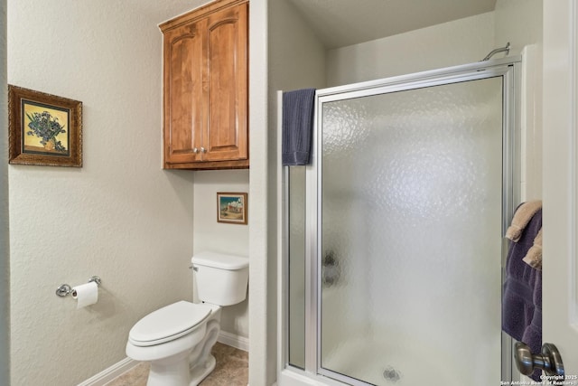 bathroom featuring a stall shower, toilet, and baseboards