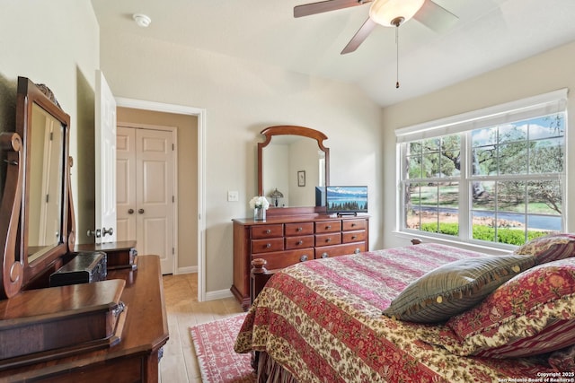 bedroom featuring ceiling fan, light wood-style floors, and lofted ceiling