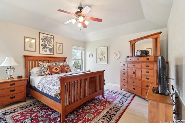 bedroom with a tray ceiling, light wood-style floors, baseboards, and ceiling fan