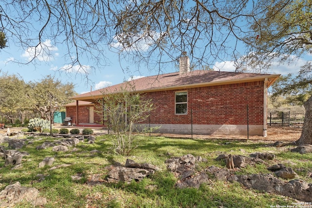 rear view of house featuring brick siding, a chimney, and a patio area