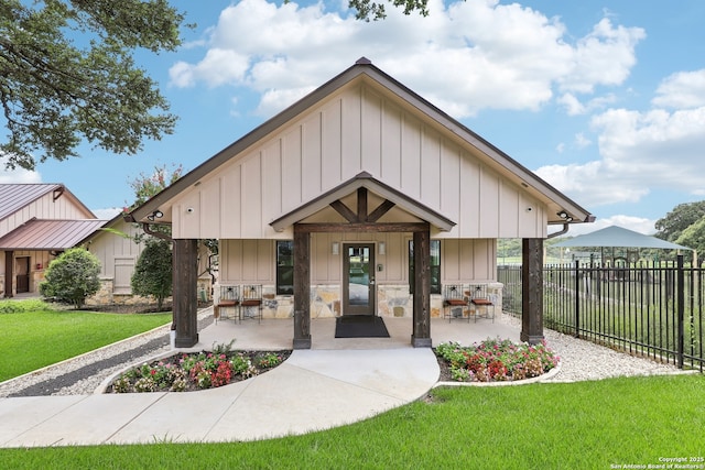 view of front of home featuring board and batten siding, a front lawn, and fence