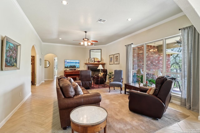 living area featuring baseboards, a ceiling fan, arched walkways, and ornamental molding