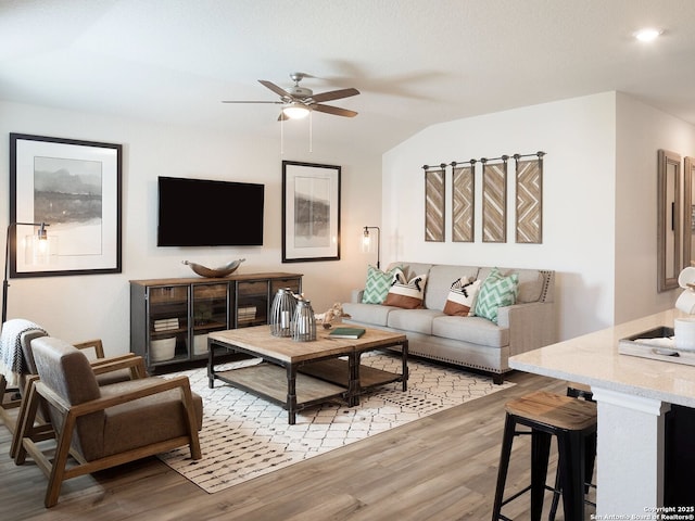 living area featuring lofted ceiling, light wood-style floors, and ceiling fan