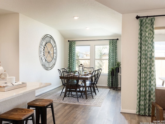 dining area with lofted ceiling, wood finished floors, and baseboards