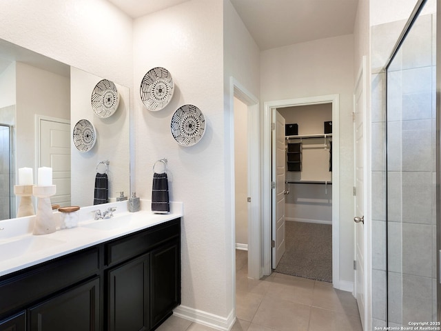 full bath featuring tile patterned floors, a walk in closet, a sink, a tile shower, and double vanity