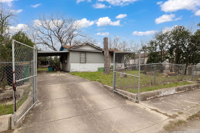 view of front of house featuring a front lawn, a gate, driveway, fence, and an attached carport