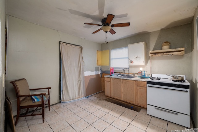 kitchen with light tile patterned floors, gas range gas stove, a sink, ceiling fan, and light brown cabinetry