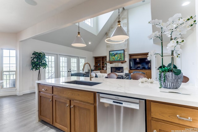 kitchen with pendant lighting, a sink, open floor plan, brown cabinetry, and dishwasher