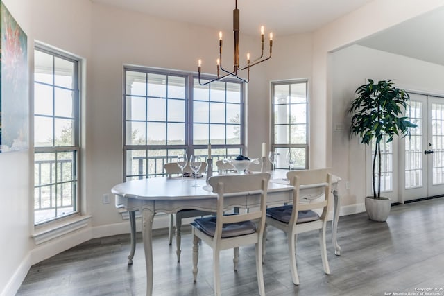 dining space with french doors, baseboards, an inviting chandelier, and wood finished floors