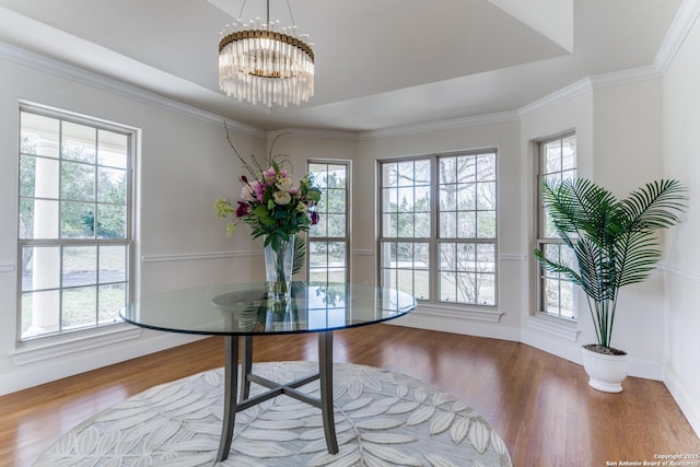 dining area featuring a raised ceiling, wood finished floors, an inviting chandelier, crown molding, and baseboards