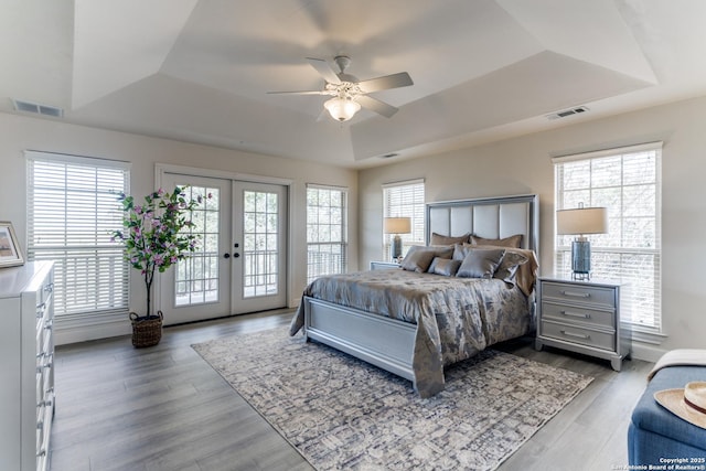 bedroom with visible vents, french doors, a raised ceiling, access to outside, and multiple windows