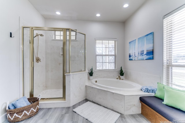 bathroom featuring a bath, wood finished floors, recessed lighting, and a marble finish shower