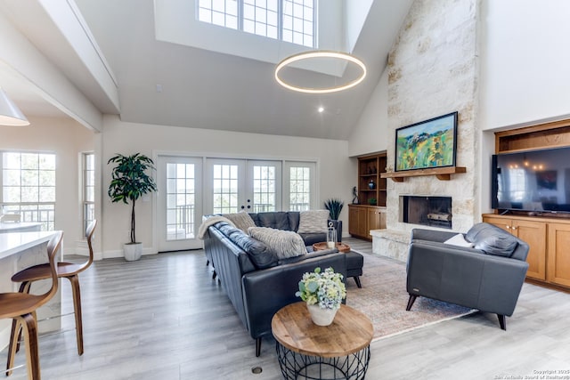 living area featuring a fireplace, a high ceiling, french doors, and light wood-style flooring