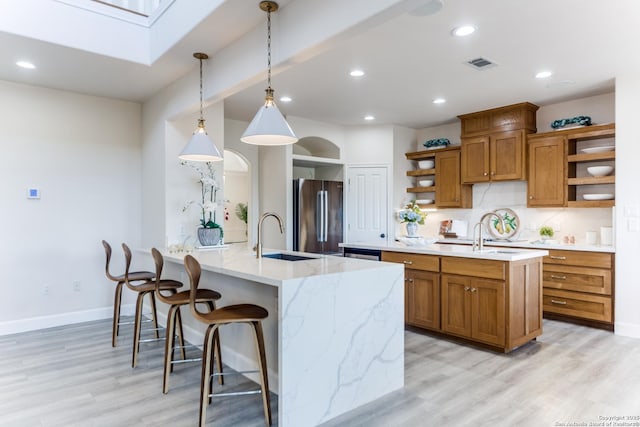 kitchen featuring visible vents, open shelves, high end fridge, a sink, and brown cabinets