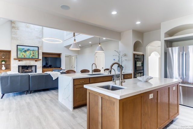 kitchen featuring dobule oven black, a kitchen island with sink, freestanding refrigerator, and a sink