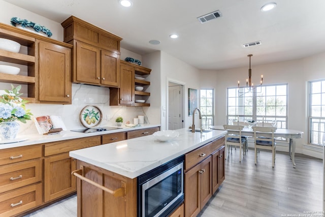 kitchen featuring visible vents, open shelves, a sink, stainless steel microwave, and black electric stovetop