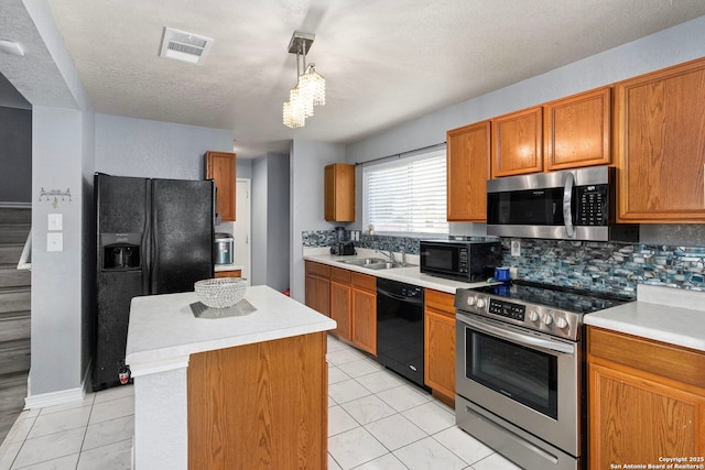 kitchen featuring a kitchen island, light countertops, brown cabinets, black appliances, and a sink