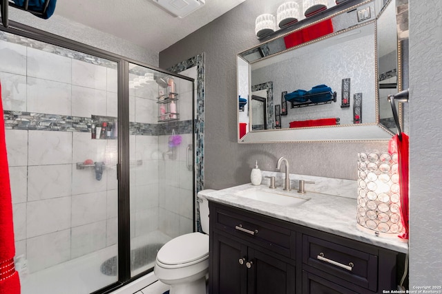 full bath with vanity, toilet, a shower stall, and a textured wall