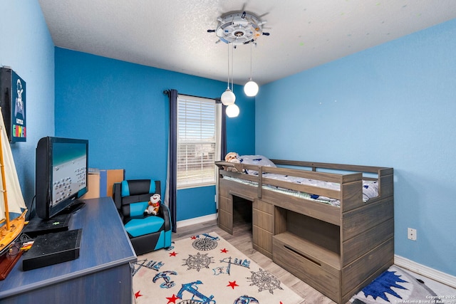 bedroom featuring wood finished floors, baseboards, and a textured ceiling