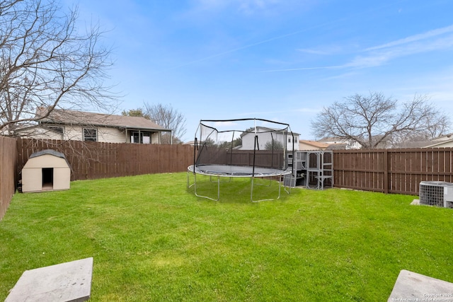 view of yard with cooling unit, a trampoline, and a fenced backyard