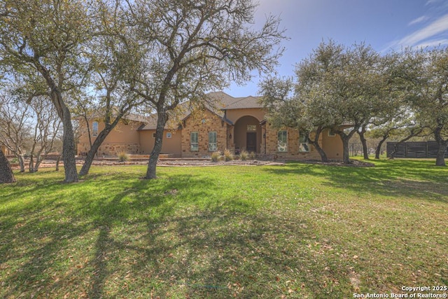 view of front of house with stucco siding, a front yard, and fence