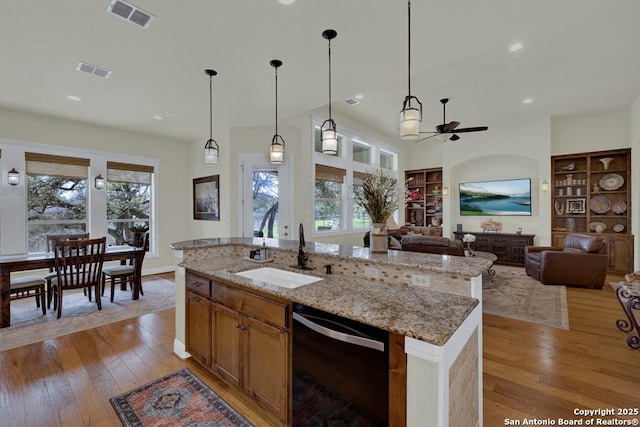 kitchen featuring light wood finished floors, visible vents, dishwasher, and a sink