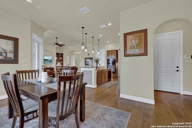 dining area featuring visible vents, hardwood / wood-style flooring, recessed lighting, arched walkways, and baseboards