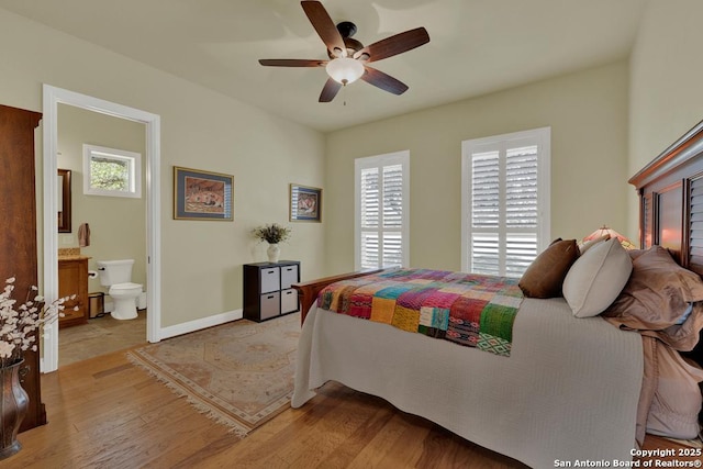 bedroom with ensuite bath, light wood-style flooring, a ceiling fan, and baseboards