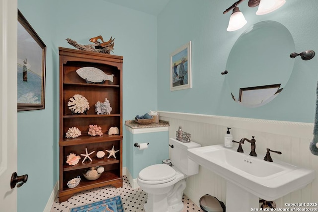 bathroom with a sink, a wainscoted wall, and toilet