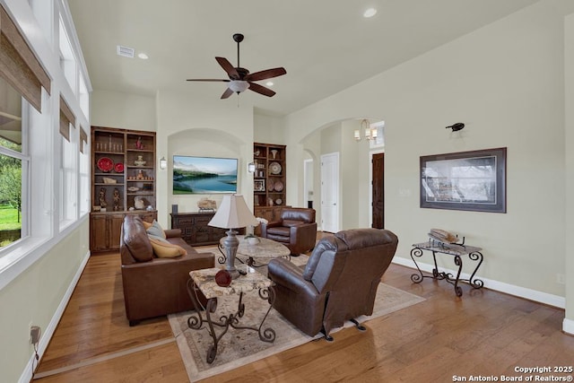 living area featuring recessed lighting, baseboards, arched walkways, and wood finished floors