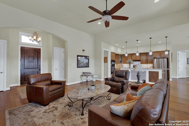 living area featuring recessed lighting, baseboards, arched walkways, and wood finished floors