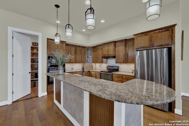 kitchen with dark wood-type flooring, light stone counters, backsplash, freestanding refrigerator, and black / electric stove