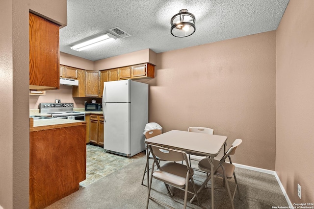 kitchen with visible vents, black microwave, under cabinet range hood, freestanding refrigerator, and electric range