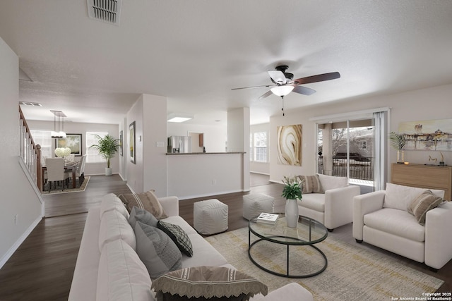 living room featuring visible vents, baseboards, wood finished floors, and a ceiling fan