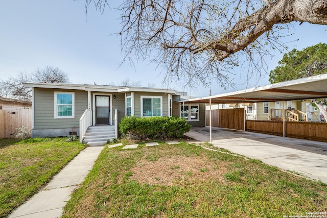 view of front of house featuring an attached carport, concrete driveway, a front yard, and fence