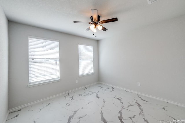 spare room with plenty of natural light, marble finish floor, and baseboards