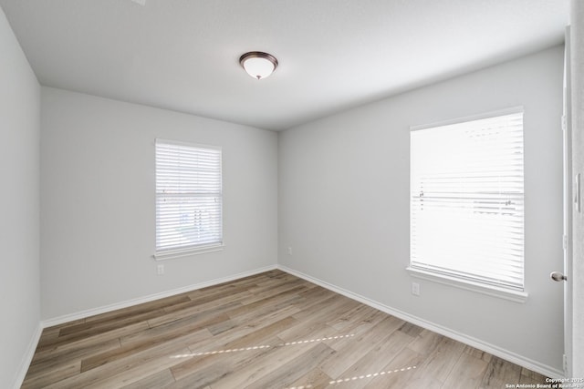 unfurnished room with light wood-type flooring and baseboards