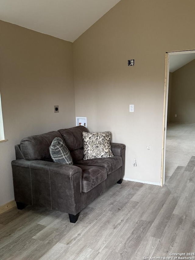 living room with lofted ceiling, light wood-style floors, and baseboards