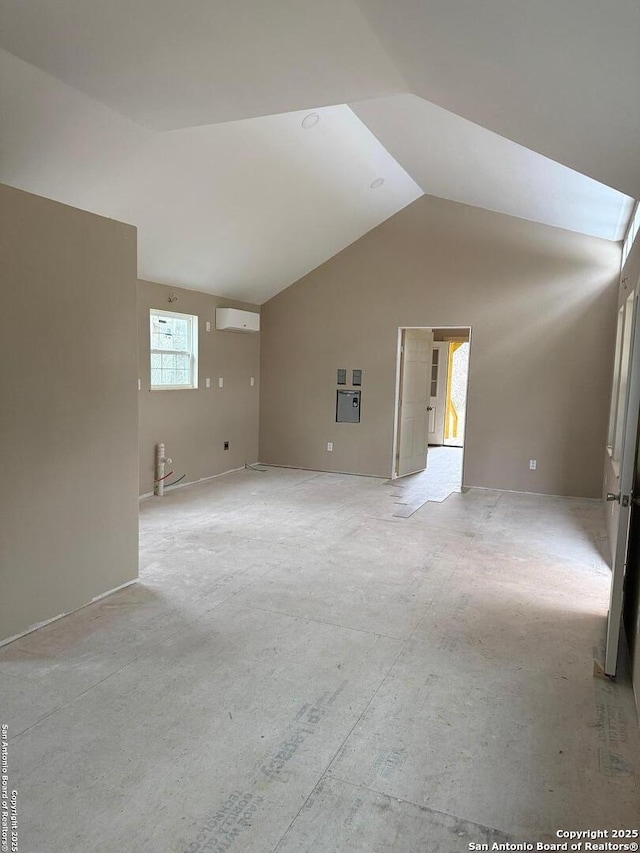 empty room with a wall mounted air conditioner and vaulted ceiling