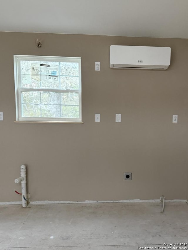 laundry room with electric dryer hookup, a wall unit AC, and laundry area