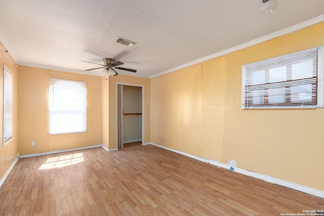 spare room with visible vents, ceiling fan, baseboards, ornamental molding, and wood finished floors