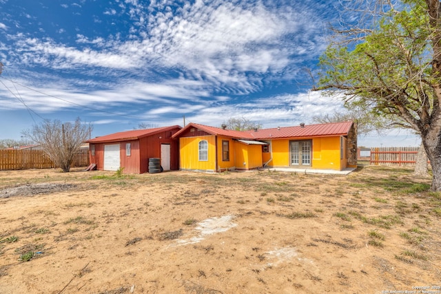 view of front of home with an attached garage, fence, and metal roof