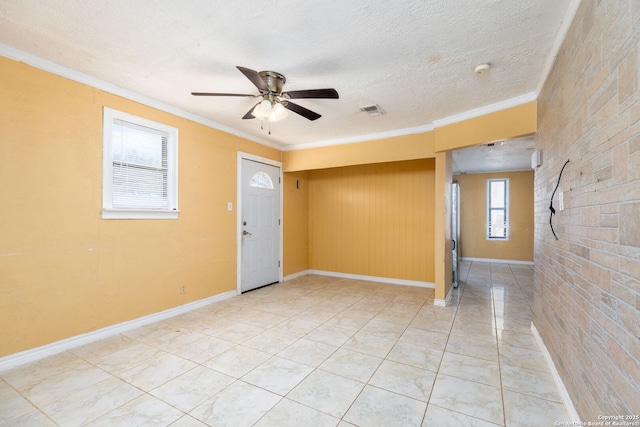 empty room featuring visible vents, crown molding, baseboards, a textured ceiling, and a ceiling fan