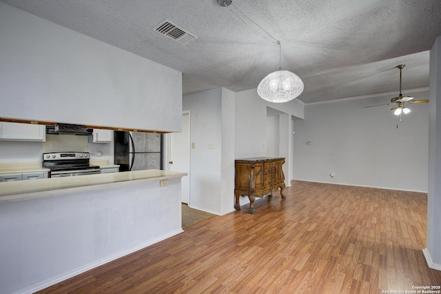 kitchen with visible vents, under cabinet range hood, light wood-type flooring, light countertops, and stainless steel appliances