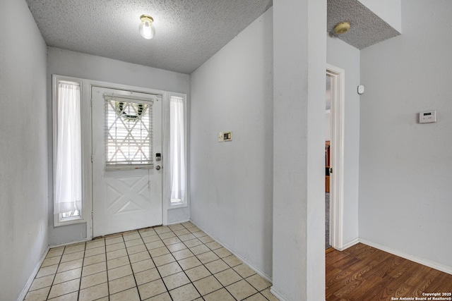 foyer entrance featuring light tile patterned floors, baseboards, and a textured ceiling