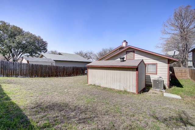 back of property featuring cooling unit, a lawn, a chimney, and fence