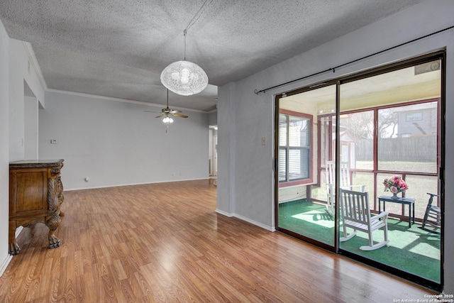 empty room featuring light wood-type flooring, a textured ceiling, ceiling fan, and ornamental molding