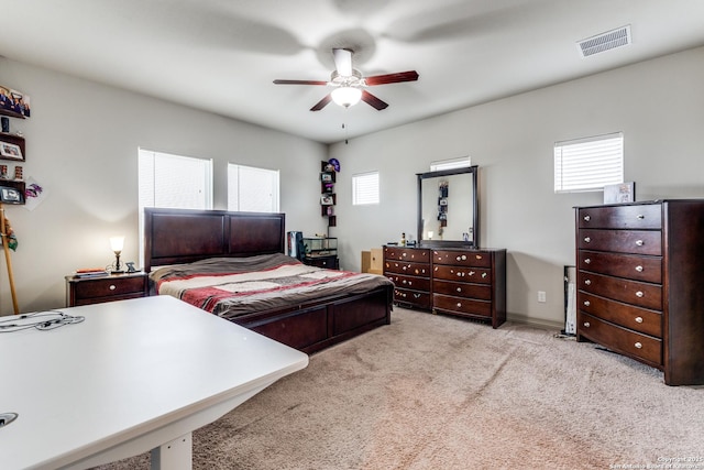 carpeted bedroom featuring a ceiling fan and visible vents