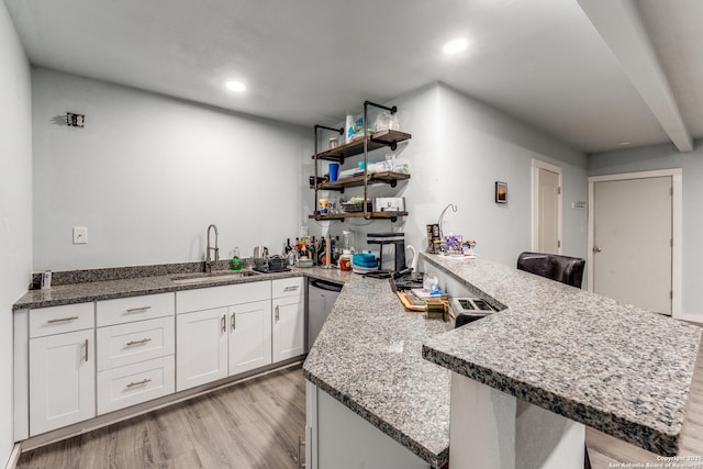 kitchen with a sink, dishwasher, a peninsula, white cabinets, and open shelves